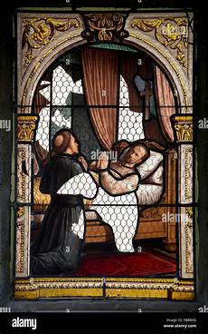 A damaged stained glass window scene depicting a dying person praying