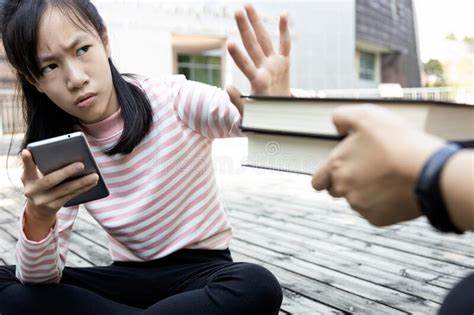 Asian Child Girl is Avoiding Reading Book,she Wants To Use a Mobile ...