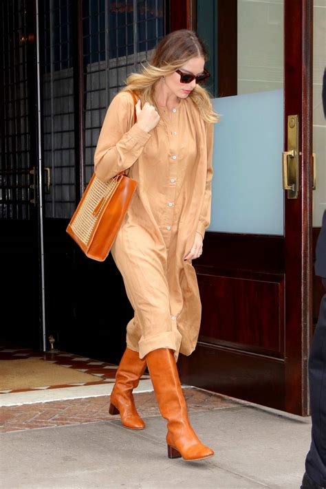 Margot Robbie wears a buttoned down beige dress and burnt orange  