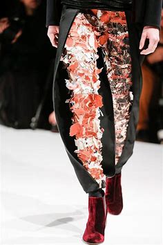 Closeup of pants being worn on the runway where gray pants a split open and another pair are underneath
