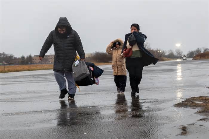 Migrants leave their tents at Floyd Bennett Field to board school buses bound for a local high school.