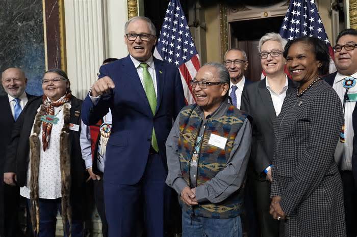 Washington Gov. Jay Inslee, third from left, stands with Chair Gerry Lewis of the Yakama Nation, fourth from left, as they and others pose for a photo following a ceremonial signing ceremony in Washington, Friday, Feb. 23, 2024. The ceremonial signing is an agreement between the Biden administration and state and Tribal governments to work together to protect salmon and other native fish, honor obligations to Tribal nations, and recognize the important services the Columbia River System provides to the economy of the Pacific Northwest. (AP Photo/Susan Walsh)