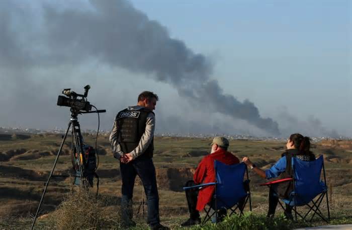 Journalists observe as smoke rises over Gaza, amid the ongoing conflict between Israel and the Palestinian Islamist group Hamas, as seen from southern Israel, December 26, 2023.