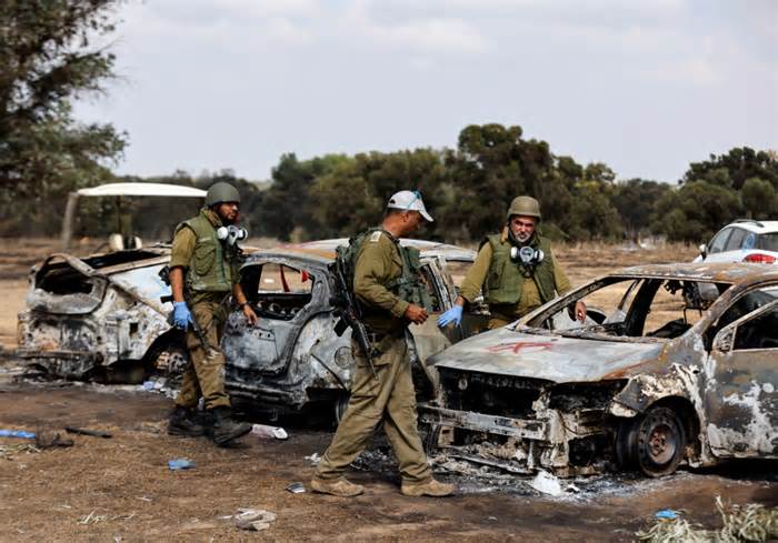 Israeli soldiers inspect the burnt cars of festival-goers at the site of an attack on the Nova Festival by Hamas gunmen from Gaza, near Israel