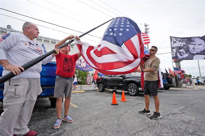 Supporters of former President Donald Trump prepare to raise an American flag as they wait for his arrival at the Federal Courthouse on March 1, 2024, in Fort Pierce, Fla.