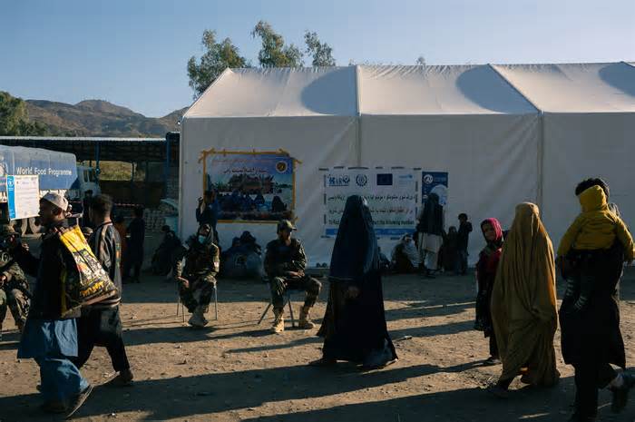 Afghan returnees pass Taliban soldiers at the Torkham crossing Nov. 11.