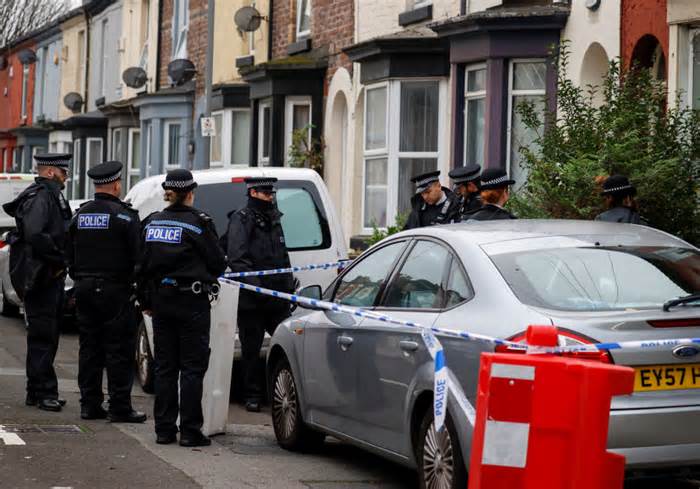 Police officers keep guard outside a house in the Kensington area where counter-terrorism officers arrested men after a vehicle exploded outside Liverpool Women