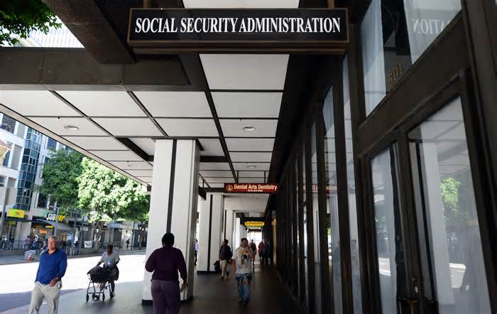 Pedestrians walk past Social Security Administration office