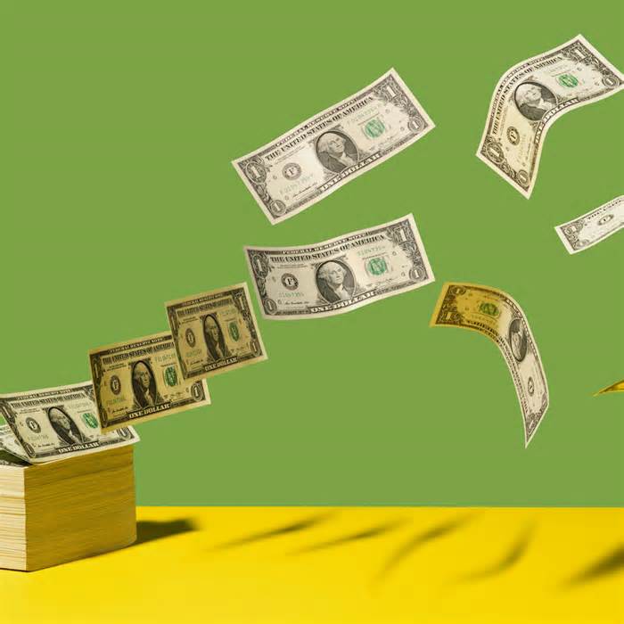 Stack of US $1 bills with bills flying away on yellow shelf, green background
