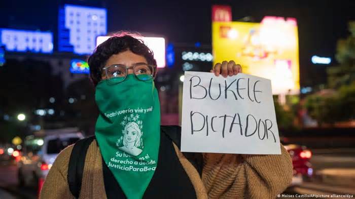 San Salvador, 5 de febrero de 2024. Una feminista con el rostro tapado muestra un cartel con la leyenda 