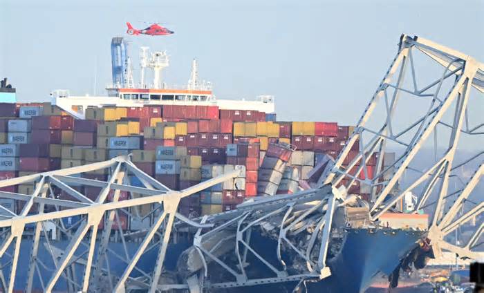 The steel frame of the Francis Scott Key Bridge sit on top of a container ship after the bridge collapsed collapsed in Baltimore, Maryland, on March 26, 2024. The bridge collapsed after being struck by a container ship, sending multiple vehicles and up to 20 people plunging into the harbor below. 