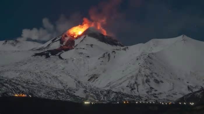 Snowy Mount Etna spurts lava into night sky