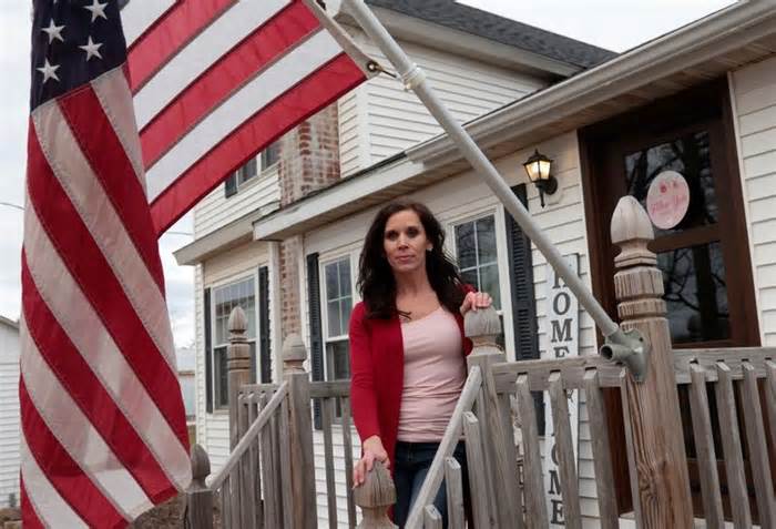 Michigan Republican Bree Moeggenberg poses next to an American flag in front of her home in Mount Pleasant