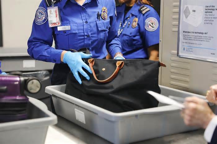 a tsa agent searches a bag at an airport security checkpoint