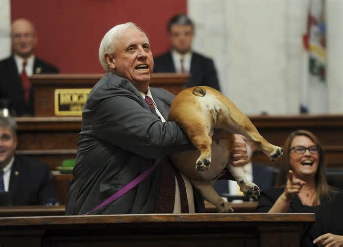 FILE - West Virginia Gov. Jim Justice holds up his dog Babydog's rear end as a message to people who've doubted the state as he comes to the end of his State of the State speech in the House chambers, Jan. 27, 2022, in Charleston, W.Va. The two-term governor is set to give his final State of the State speech to lawmakers on Wednesday, Jan. 10, 2024. (Chris Dorst/Charleston Gazette-Mail via AP, File)