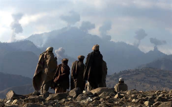 Afghan fighters watch explosions from US bombings in the Tora Bora mountains, 2001
