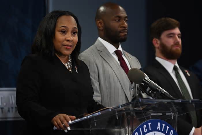 Fulton County prosecutor Nathan J. Wade, center, stands beside Fulton County District Attorney Fani T. Willis as she speaks during a news conference at the Fulton County Government building on Monday in Atlanta.