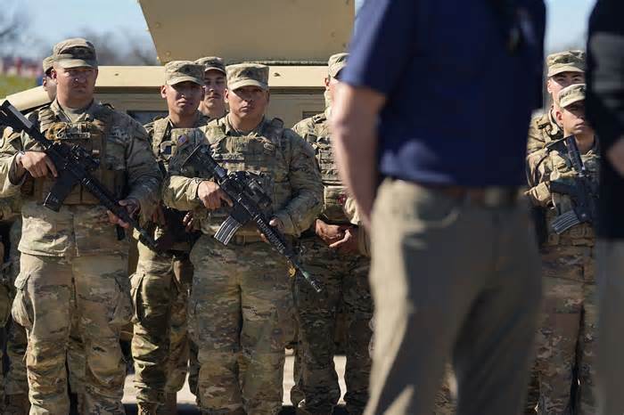 Members of the National Guard stand as Texas Gov. Greg Abbott (R) and fellow governors hold a news conference along the Rio Grande to discuss immigration issues at the border earlier this month.