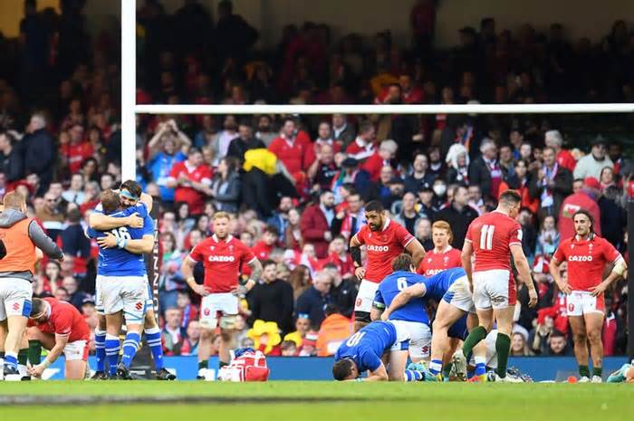 Italy players celebrate their win in front of a dejected Welsh squad after a last minute try
