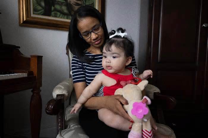 Romelia Farinas poses with her 6-month-old daughter, Amaia, inside a family home on Monday, Jan. 8, 2024, in western Miami. Farinas was six months pregnant with Amaia when she took the nursing exam about a year ago. She passed but is unable to obtain her license to practice because the New York State Education Department is investigating her for-profit college. They have told Farinas to re-take the exam, but English is not her first language and she studied for months the first time around. It would take time away from my baby to study again and I cant do that, said Farinas.