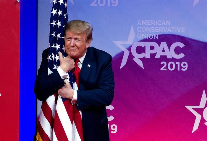 President Donald Trump hugs the American flag as he arrives to speak at Conservative Political Action Conference, CPAC 2019, in Oxon Hill, Md., on Saturday.