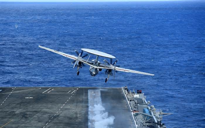 An E-2 Hawkeye radar aircraft launches from a US carrier at sea. US strike groups maintain a constant watch across hundreds of miles of sea and land using their Hawkeyes