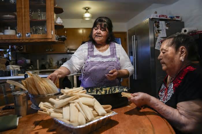 Noelia Sanchez, center, and her mother Aurora Sandoval make tamales together at the family home Tuesday, Dec. 26, 2023, in Chicago. When she was 1, Sanchez and her mother, who had no work documents, were rounded up with dozens of other immigrants in a Texas town near the border. The U.S.-born child and her mother were forced to go to Mexico along with hundreds of thousands of other people. (AP Photo/Erin Hooley)