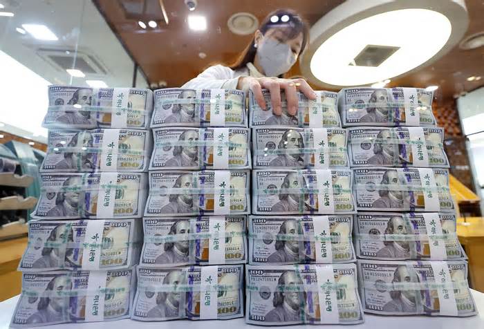 An employee sorts U.S. dollars at a bank branch in Seoul./Yonhap News