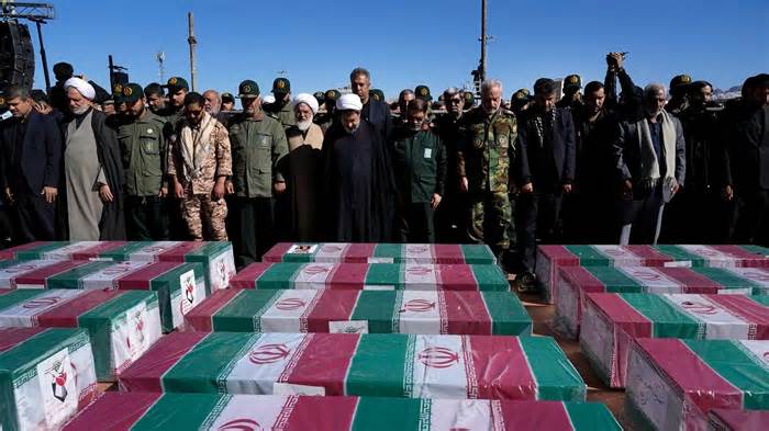People pray over the flag-draped coffins of victims of the Jan. 3 attacks during their funeral ceremony in the city of Kerman, Iran, on Friday, Jan. 5.