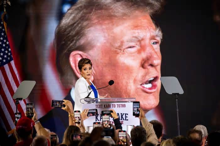 Kari Lake looks at the audience while a video of former President Donald Trump plays on a screen during an announcement rally at Jetset Magazine in Scottsdale on Oct. 10, 2023.
