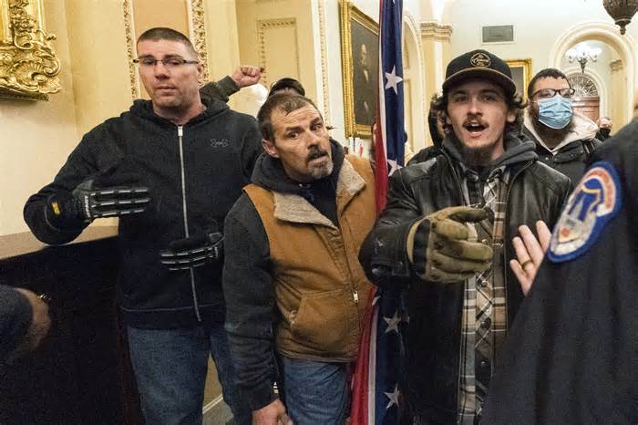 FILE - Michael Sparks, left, and Kevin Seefried, second from left, as they and other insurrectionists loyal to President Donald Trump are confronted by U.S. Capitol Police officers outside the Senate Chamber inside the Capitol in Washington, Jan. 6, 2021. Sparks, the first rioter to enter the Capitol building during the Jan. 6, 2021, attack has been convicted of charges that he interfered with police and obstructed Congress from certifying President Joe Biden's 2020 electoral victory.(AP Photo/Manuel Balce Ceneta, File)