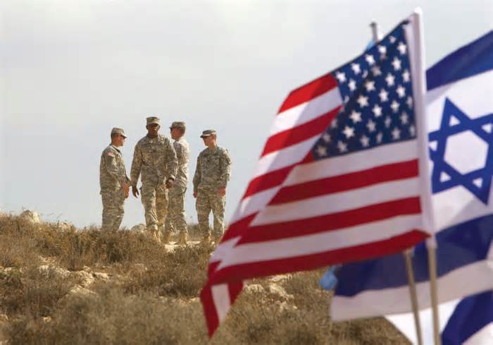 US SOLDIERS stand in the background next to Israeli and American flags during an exercise in Israel.