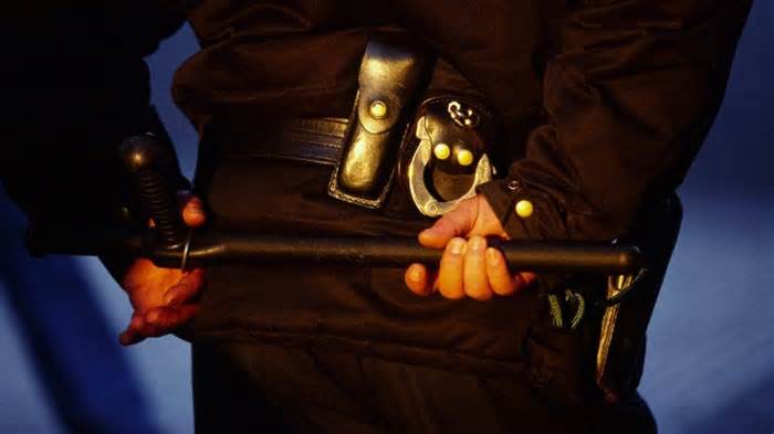 Photo illustration shows a law enforcement officer carrying a billy club, also sometimes referred to as a police baton.