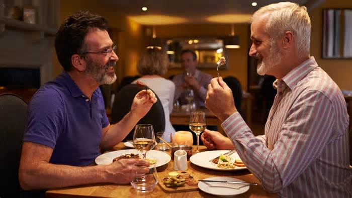 Middle aged male couple eating evening meal in a restaurant