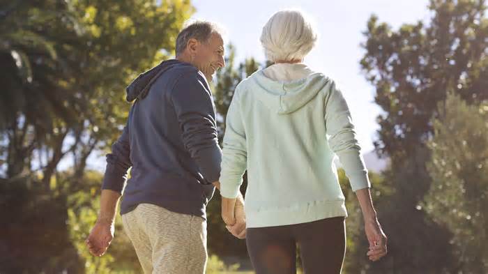 retired senior couple walk hold hands_iStock-184312820