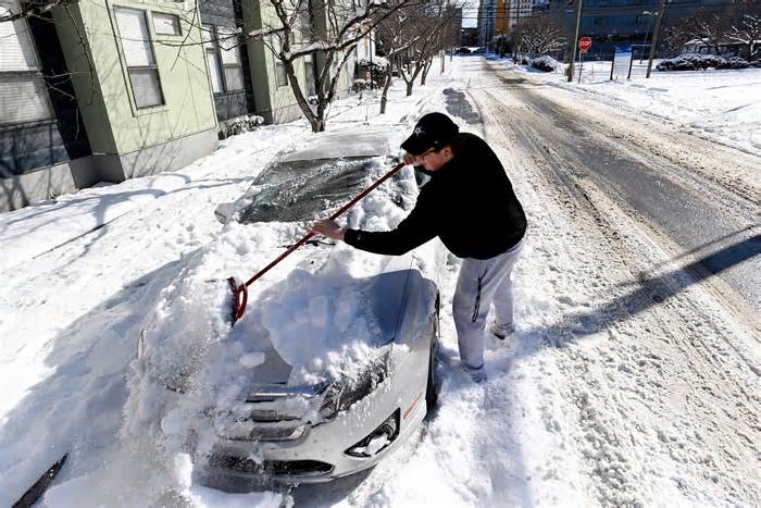 Vanderbilt University student Warner Myntti brushes snow off his car along on Jan. 16, 2024, in Nashville, Tennessee.