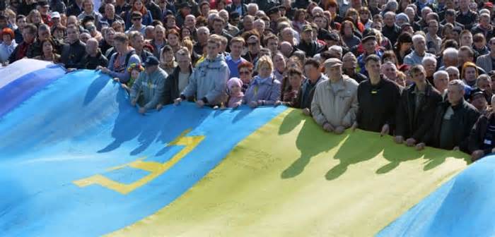 People hold a huge flag, a combination of Ukrainian and Crimean Tatar flags, on Independence Square in Kyiv on March 23, 2014. (Sergei Supinsky/AFP via Getty Images)