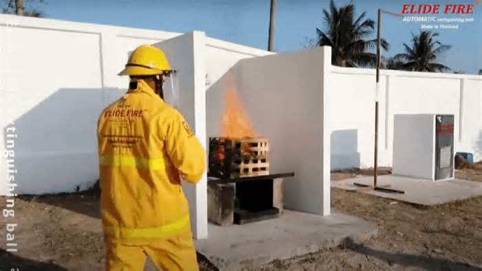 A GIF of an Elide Fire employee demonstrating the Fire Extinguishing Ball in a crate on fire.