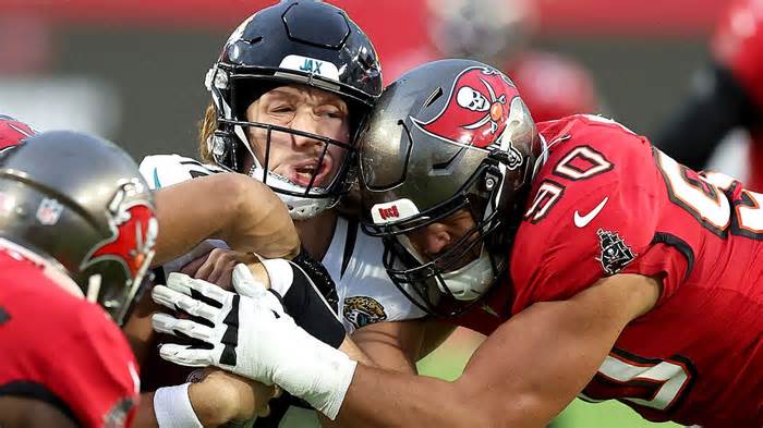 Trevor Lawrence #16 of the Jacksonville Jaguars is hit by Logan Hall #90 of the Tampa Bay Buccaneers during the second quarter at Raymond James Stadium on December 24, 2023 in Tampa, Florida.
