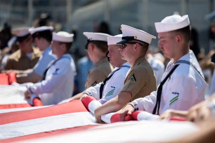 U.S. military members hold a flag.