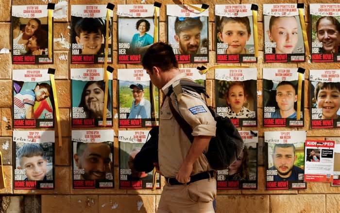 An Israeli soldier walks past a board displaying posters of Israeli hostages last month