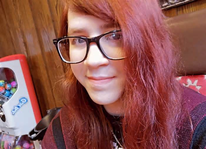 Amelia with long red hair and black rimmed glasses