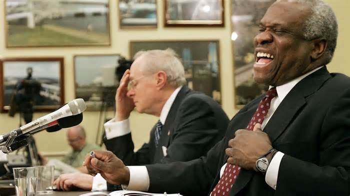 Justice Clarence Thomas (right) laughs.