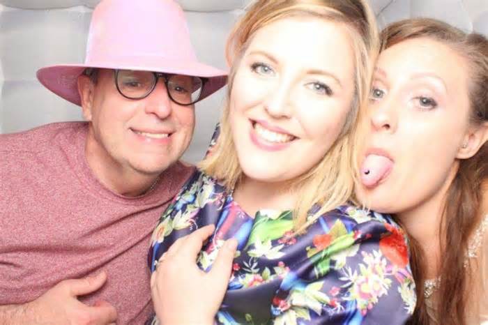 Rebecca with her sister and dad - her sister is sticking her tongue out and her dad is wearing a pink hat