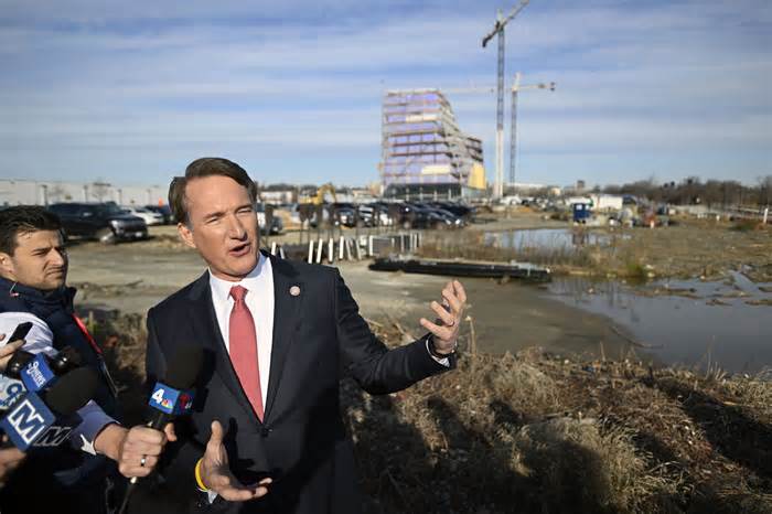 Virginia Governor Glenn Youngkin discusses the site of a new sports arena in Alexandria. The construction of the new Virginia Tech building is in background;