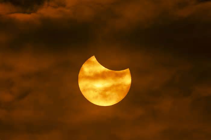 The annular eclipse peeks through partly cloudy skies over Boise on Saturday.