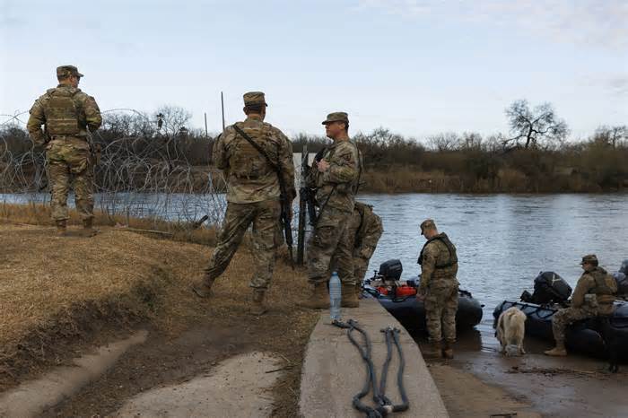 Texas National Guard soldiers wait near a boat ramp where law enforcement officers enter the Rio Grande at Shelby Park on Friday in Eagle Pass, Tex. (Michael Gonzalez/Getty Images)