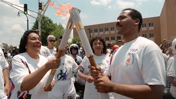 Coretta Scott King (L), widow of civil rights leader Martin Luther King Jr., passes the Olympic Flame to her son Dexter Scott King on July 19, 1996, in Atlanta. - Michel Gangne/AFP/Getty Images