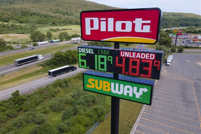 FILE - Trucks and cars drive by a Pilot Travel Center sign displaying fuel prices in Bath, New York, on Monday, June 20, 2022. Warren Buffett’s Berkshire Hathaway says the billionaire Haslam family tried to bribe at least 15 executives at the Pilot truck stop chain with millions of dollars to inflate the company’s profits this year because that would force Berkshire to pay more for the Haslams’ remaining 20% stake in the company. (AP Photo/Ted Shaffrey, File)