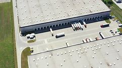 Premium stock video - Aerial shot of industrial warehouse loading dock where many truck with semi trailers load merchandise